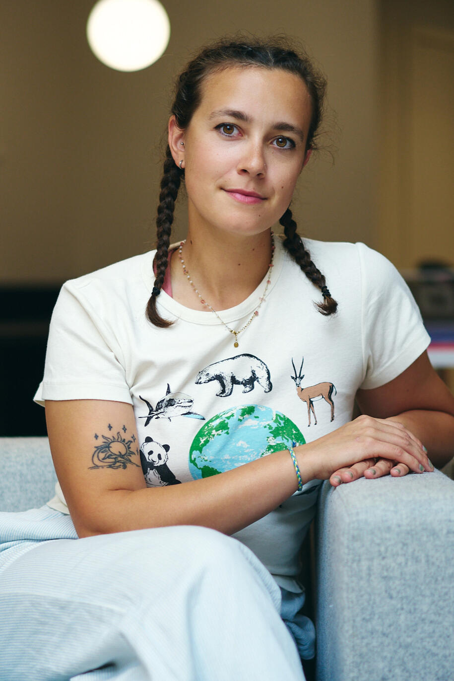 Indiemoon the illustrator sits in a chair with her hands cupping on the side of the chair